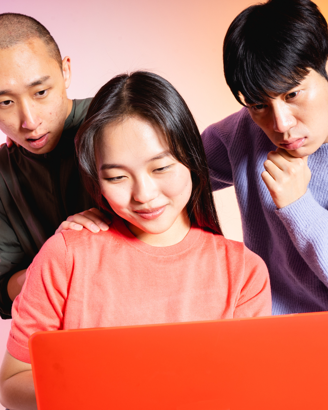 Three students gathered around a laptop